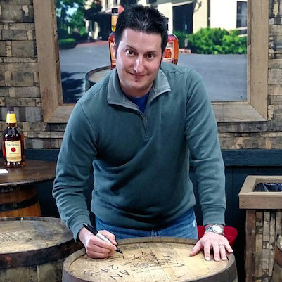 Jonathan Maisano marking a whiskey barrel